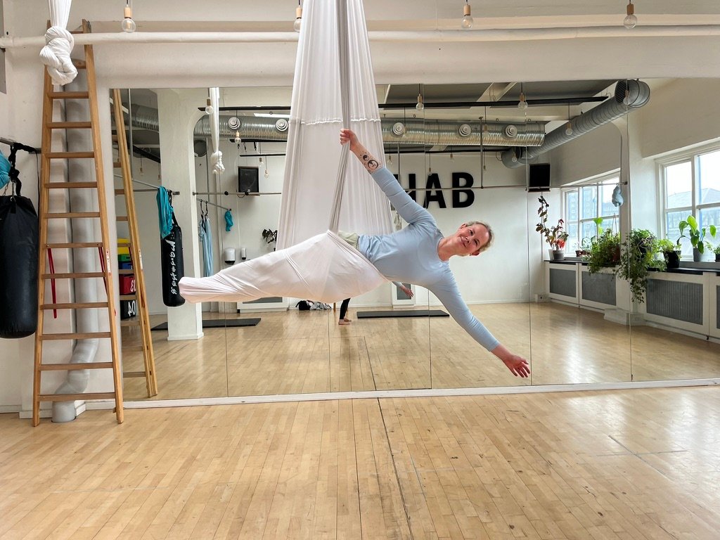 Aerial Yoga med støtte fra en hvid stofslynge