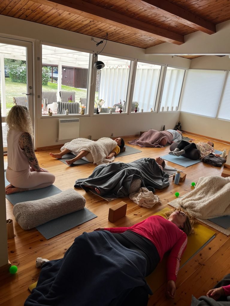Deltagere hviler på måtter under en rolig yogatime